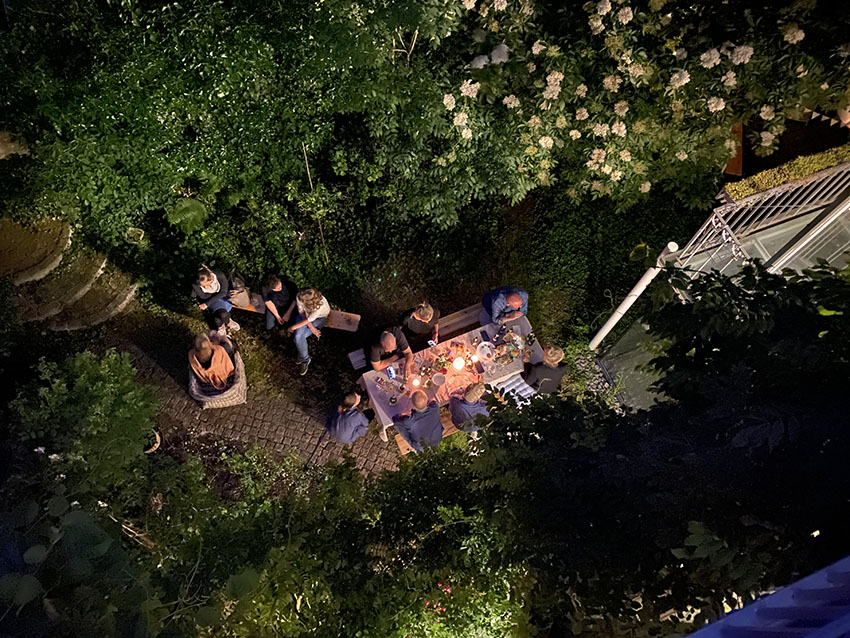 The old-town office garden with a bunch of team members sitting at a table, taken from above.